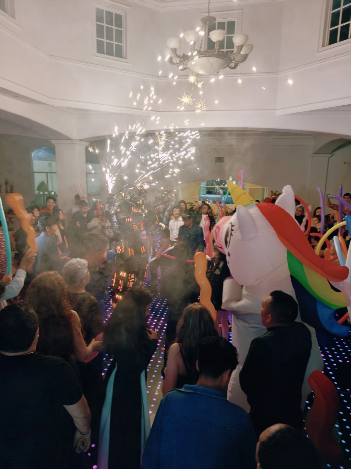 Fiesta con personajes, globos y destellos durante la batucada